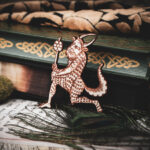 A laser cut and engraved magnet made from raw birch plywood in the shape of a satyr holding a branch from the Aberdeen Bestiary leaning against a stack of books.