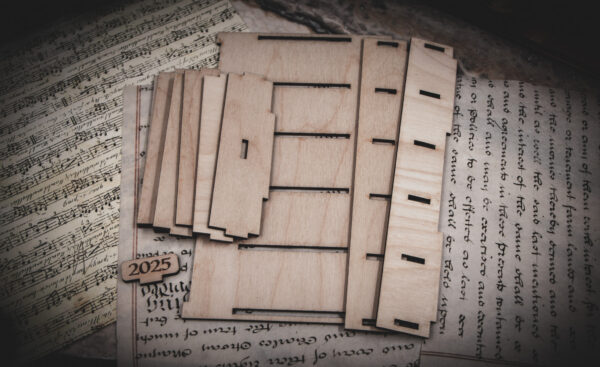 The pieces to make a mini laser cut bookshelf laid out in a group on top of various papers