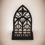 The front of an architectural book nook lantern featuring laser-cut Gothic cathedral window tracery made from 1/8 inch birch plywood painted matte black.