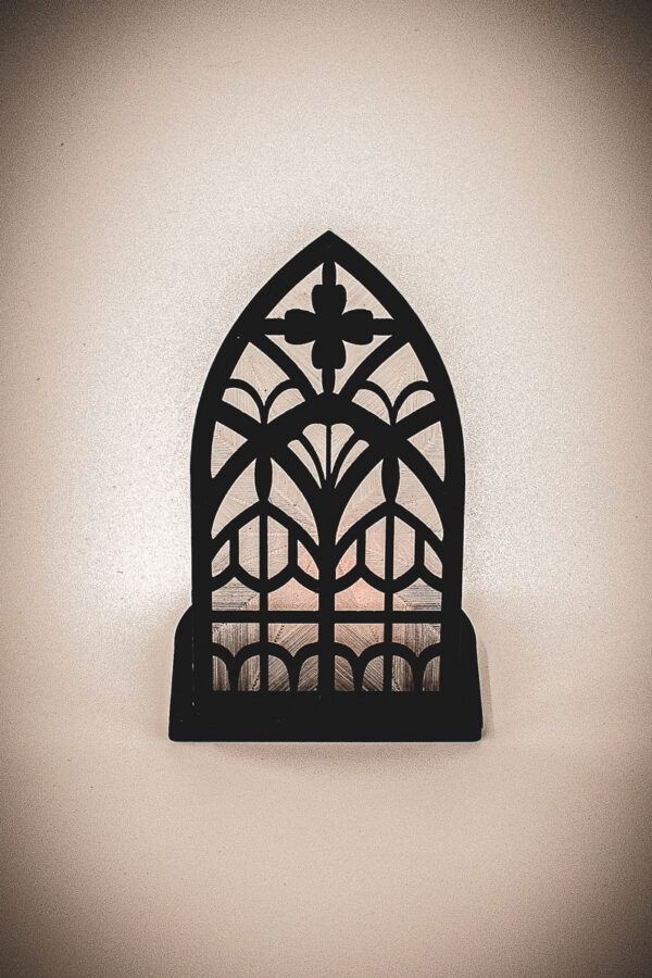 The front of an architectural book nook lantern featuring laser-cut Gothic cathedral window tracery made from 1/8 inch birch plywood painted matte black.