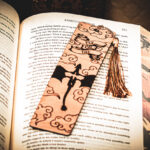 A wooden dragon rider bookmark with a gold-toned tassel, highlighting the detailed engraving of a dragon and stylized cloud patterns.
