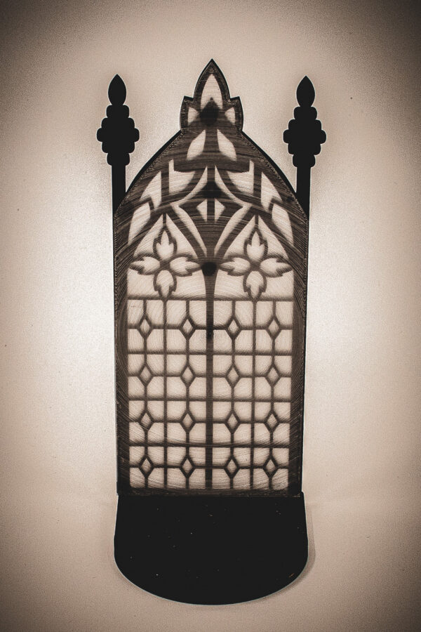 The back of an architectural book nook lantern featuring laser-cut Gothic cathedral window tracery made from 1/8 inch birch plywood painted matte black
