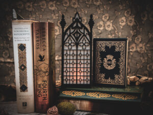 Architectural book nook lantern featuring laser-cut Gothic cathedral window tracery made from 1/8 inch birch plywood painted matte black on top of and beside books softly glowing