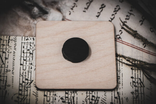 Back of square birch wood magnet featuring Hans Holbein the Younger's Danse Macabre alphabet woodcuts from 1523.