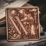 Square birch wood magnet featuring Hans Holbein the Younger's Danse Macabre alphabet letter W woodcut from 1523.