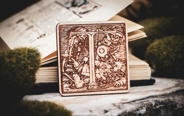 Square birch wood magnet featuring Hans Holbein the Younger's Danse Macabre alphabet letter T woodcut from 1523.