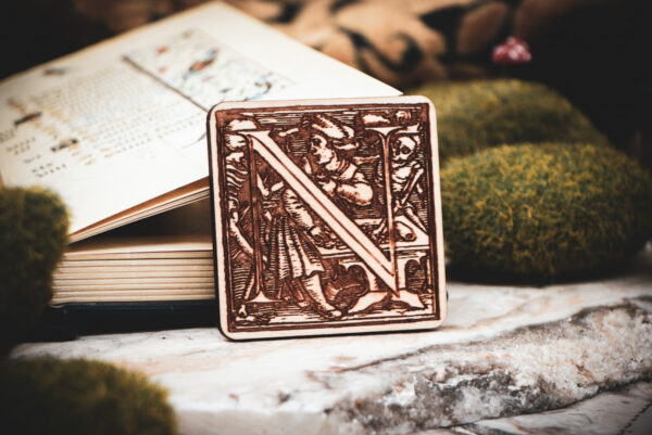 Square birch wood magnet featuring Hans Holbein the Younger's Danse Macabre alphabet letter N woodcut from 1523.