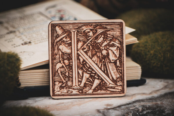Square birch wood magnet featuring Hans Holbein the Younger's Danse Macabre alphabet letter K woodcut from 1523.