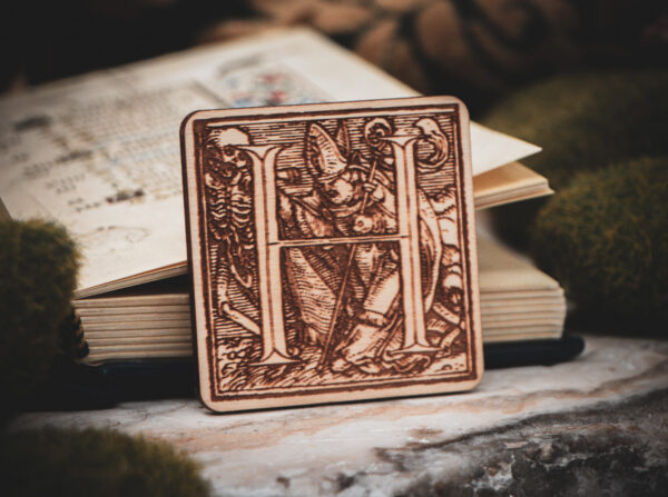 Square birch wood magnet featuring Hans Holbein the Younger's Danse Macabre alphabet letter H woodcut from 1523.