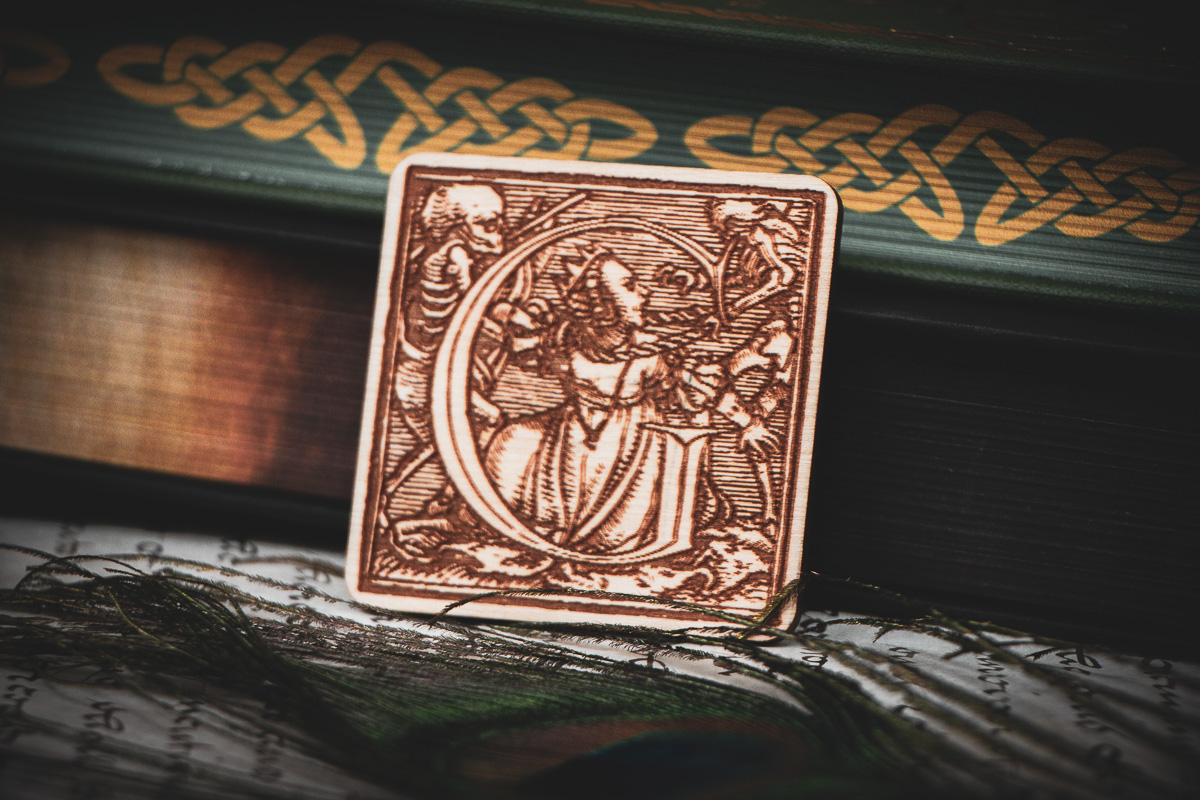 Square birch wood magnet featuring Hans Holbein the Younger's Danse Macabre alphabet letter G woodcut from 1523.