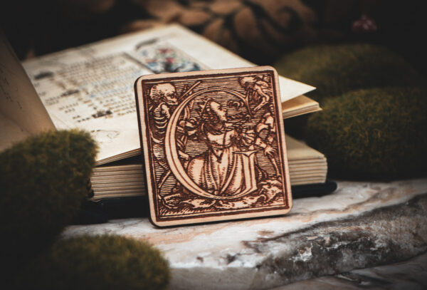 Square birch wood magnet featuring Hans Holbein the Younger's Danse Macabre alphabet letter G woodcut from 1523.