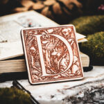 Square birch wood magnet featuring Hans Holbein the Younger's Danse Macabre alphabet letter D woodcut from 1523.