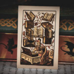 A 16th century German woodcut "9 of Books" playing card leaning against books with decorated edges.