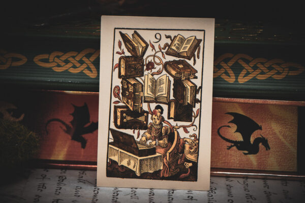 A 16th century German woodcut "9 of Books" playing card leaning against books with decorated edges.