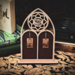 Laser cut and engraved earrings made with 1/16" birch plywood featuring the images of the Tarot cards "The Moon" and "The Star" hanging from a laser cut raw birch stand in the shape of a gothic arch in front of stacks of books.