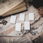 A set of 5 3D printed miniature book blanks arranged on a piece of stone surrounded by books, and papers