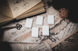A set of 5 3D printed miniature book blanks arranged on a piece of stone surrounded by books, and papers