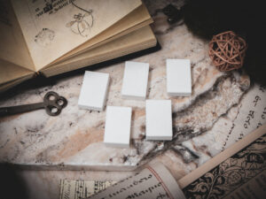 A set of 5 3D printed miniature book blanks arranged on a piece of stone surrounded by books, and papers