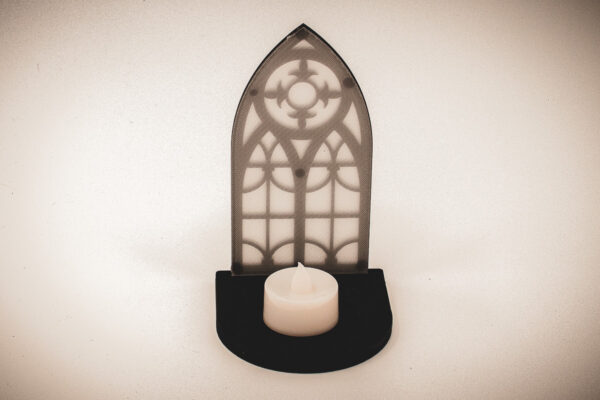 The front of an architectural book nook lantern featuring laser-cut Gothic cathedral window tracery made from 1/8 inch birch plywood painted matte black.