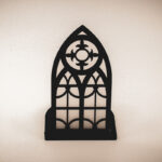 The front of an architectural book nook lantern featuring laser-cut Gothic cathedral window tracery made from 1/8 inch birch plywood painted matte black.