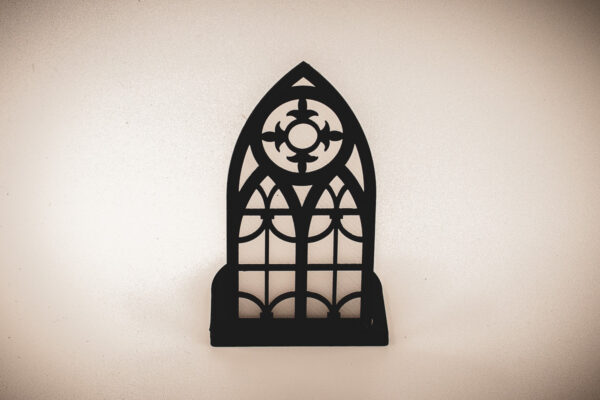 The front of an architectural book nook lantern featuring laser-cut Gothic cathedral window tracery made from 1/8 inch birch plywood painted matte black.