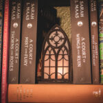 Architectural book nook lantern featuring laser-cut Gothic cathedral window tracery made from 1/8 inch birch plywood painted matte black on top of and beside books softly glowing.