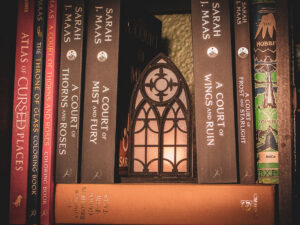 Architectural book nook lantern featuring laser-cut Gothic cathedral window tracery made from 1/8 inch birch plywood painted matte black on top of and beside books softly glowing.